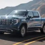 2026 GMC Sierra 1500 Denali near Shelby NC in steel blue with chrome GMC grille and Denali badging on a coastal highway