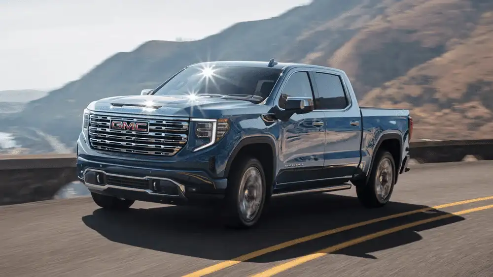 2026 GMC Sierra 1500 Denali near Shelby NC in steel blue with chrome GMC grille and Denali badging on a coastal highway