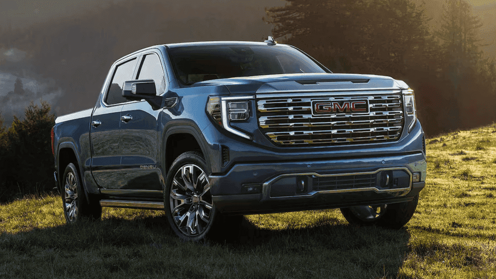 2026 GMC Sierra 1500 Denali near Shelby NC in steel blue with chrome GMC grille on a sunlit grassy hillside