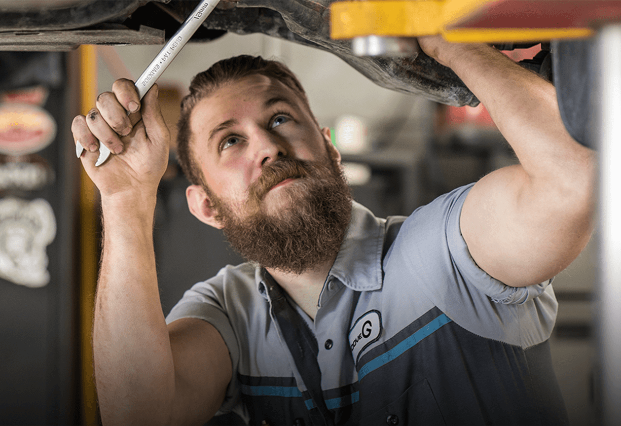 Mechanic inspecting vehicle with flashlight