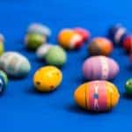 blue background with painted easter eggs sitting on the ground. Colorful painted eggs