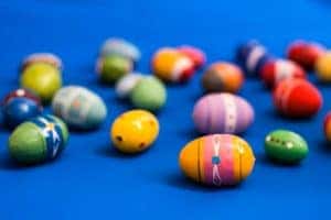 blue background with painted easter eggs sitting on the ground. Colorful painted eggs