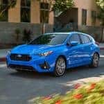 2024 Subaru Impreza Compact Car driving in urban landscaping