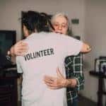 volunteer worker hugging elderly woman doing volunteer work in Fort Worth, TX