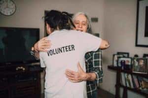 volunteer worker hugging elderly woman doing volunteer work in Fort Worth, TX