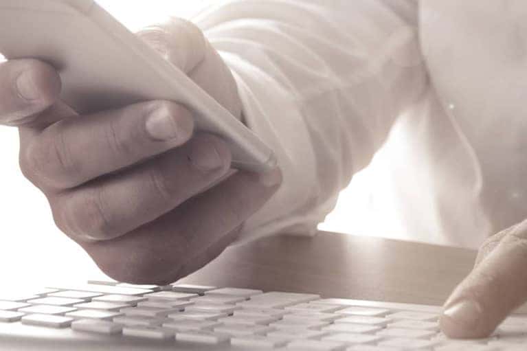 Hand holding phone with computer