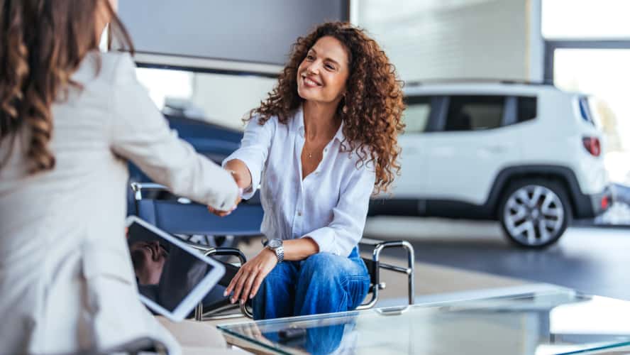 Two women shaking hands as they finalize a car sale.