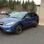 blue subaru on lot with trees