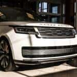 Front and side view of the 2025 Range Rover showcasing its sleek, modern design with clean lines, a distinctive grille, and premium LED headlights.