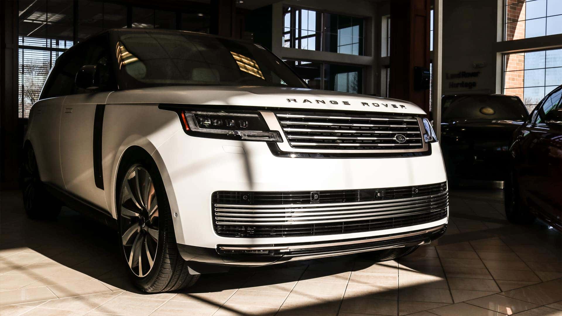 Front and side view of the 2025 Range Rover showcasing its sleek, modern design with clean lines, a distinctive grille, and premium LED headlights.