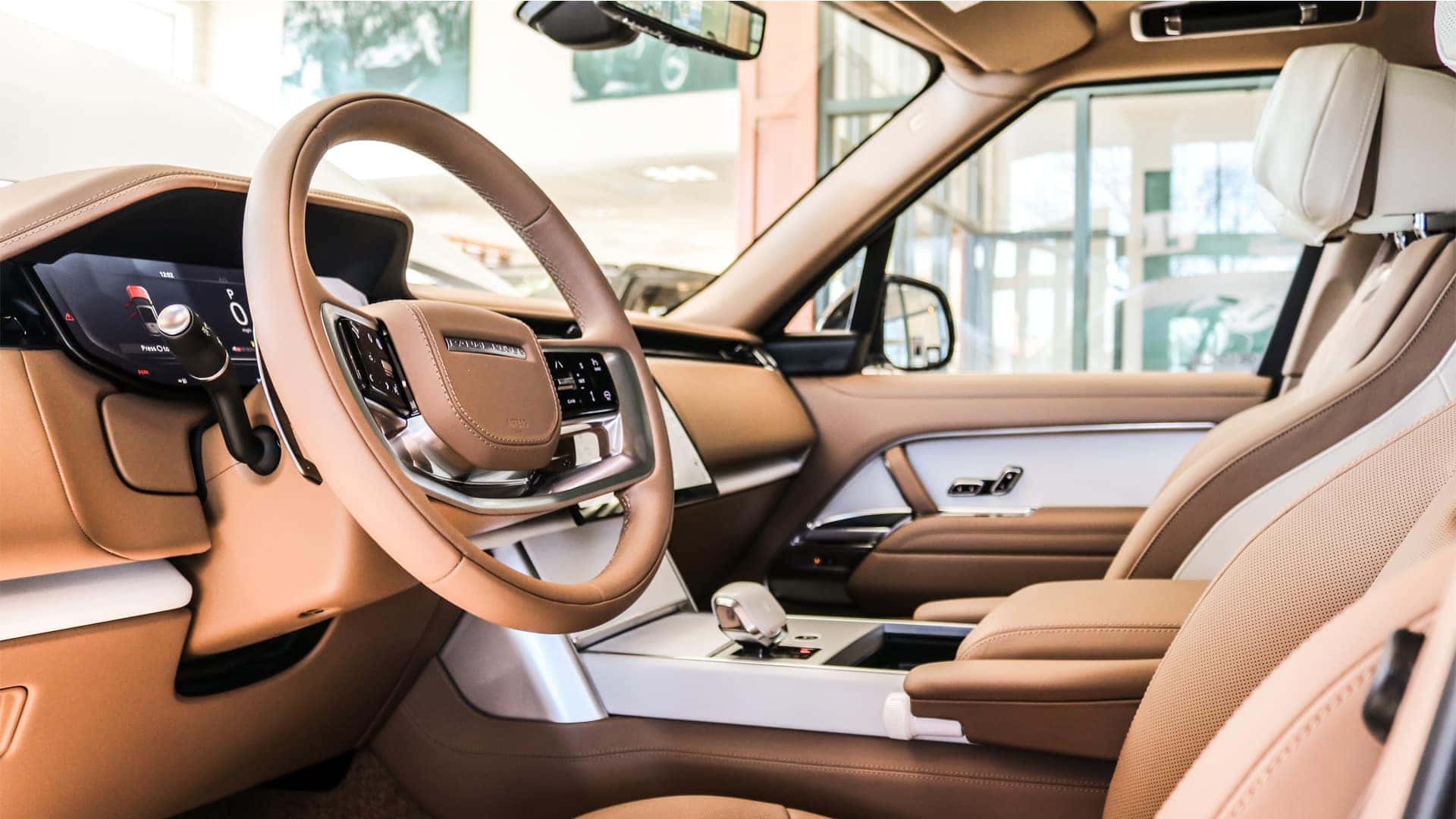 Interior view of the 2025 Range Rover highlighting its advanced technology, including a curved touchscreen display, seamless infotainment system, and integrated digital controls.
