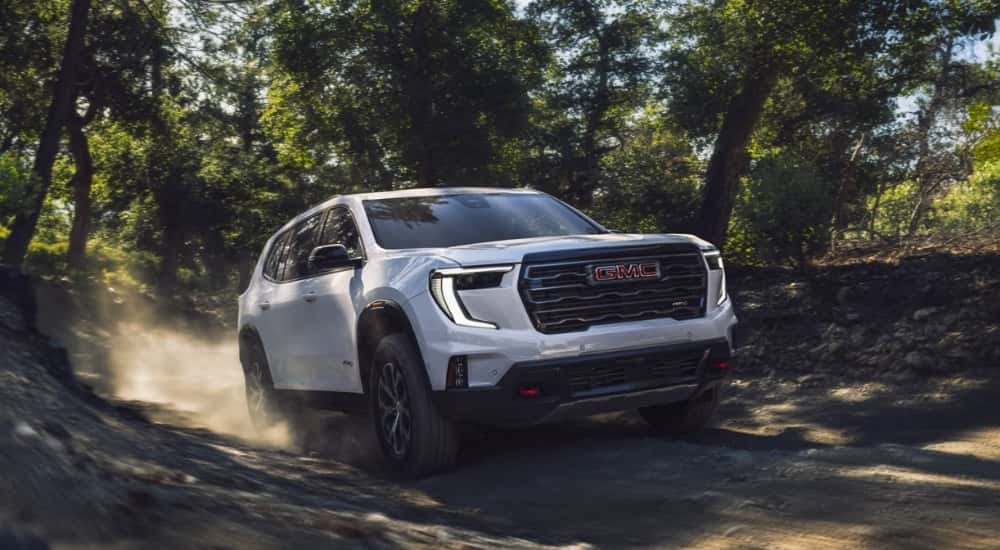 White 2024 GMC Acadia AT4 driving on a trail