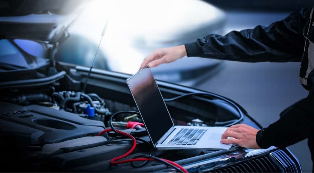 A technician using a laptop over an engine