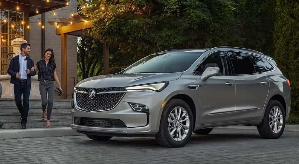 A silver 2022 Buick Enclave Avenir parked near two people on stairs.