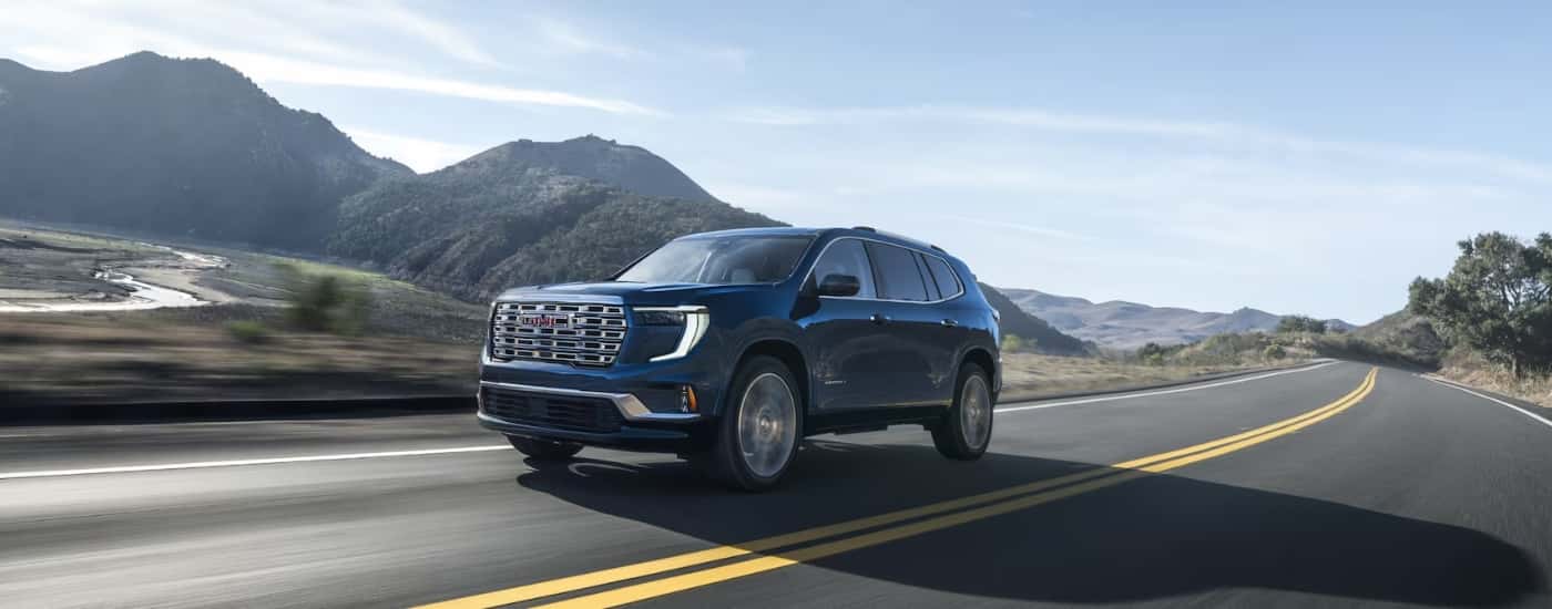 Black 2026 GMC Acadia Denali driving on an open road
