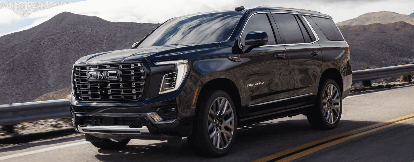Black 2026 GMC Yukon Denali driving a mountain road