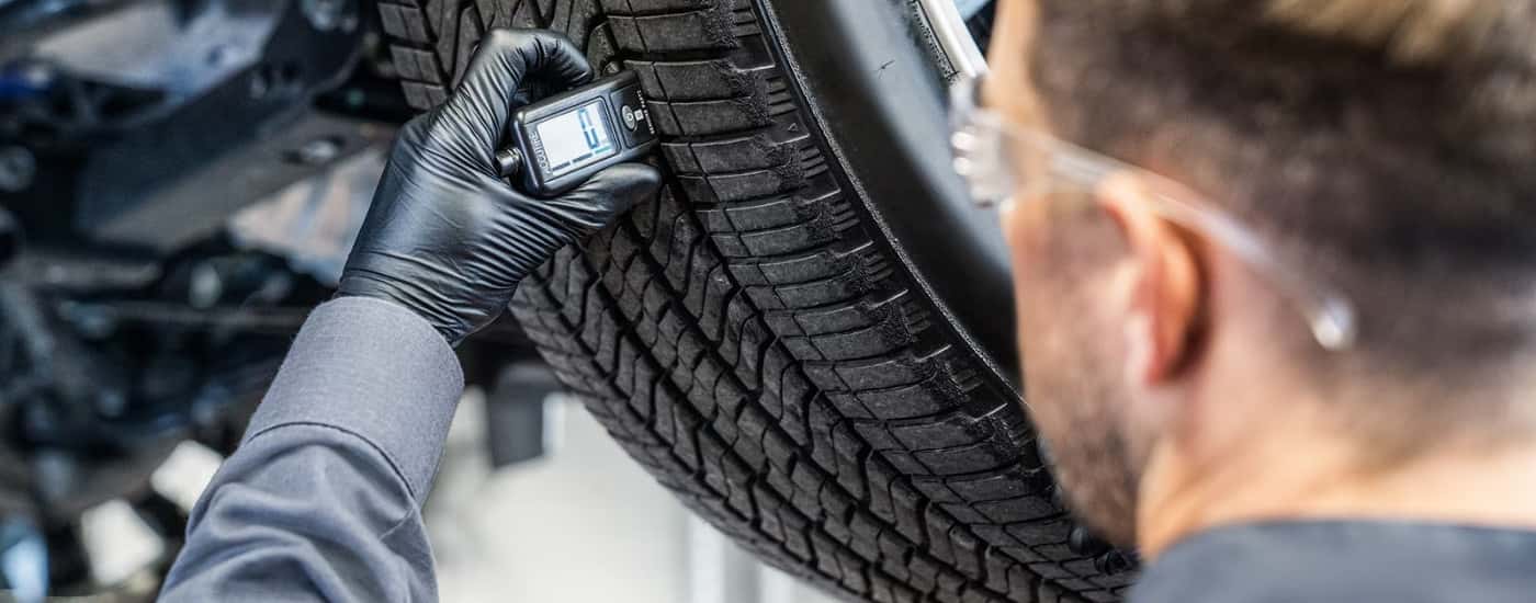 Technician checking tire tread at a GMC service center near Mason