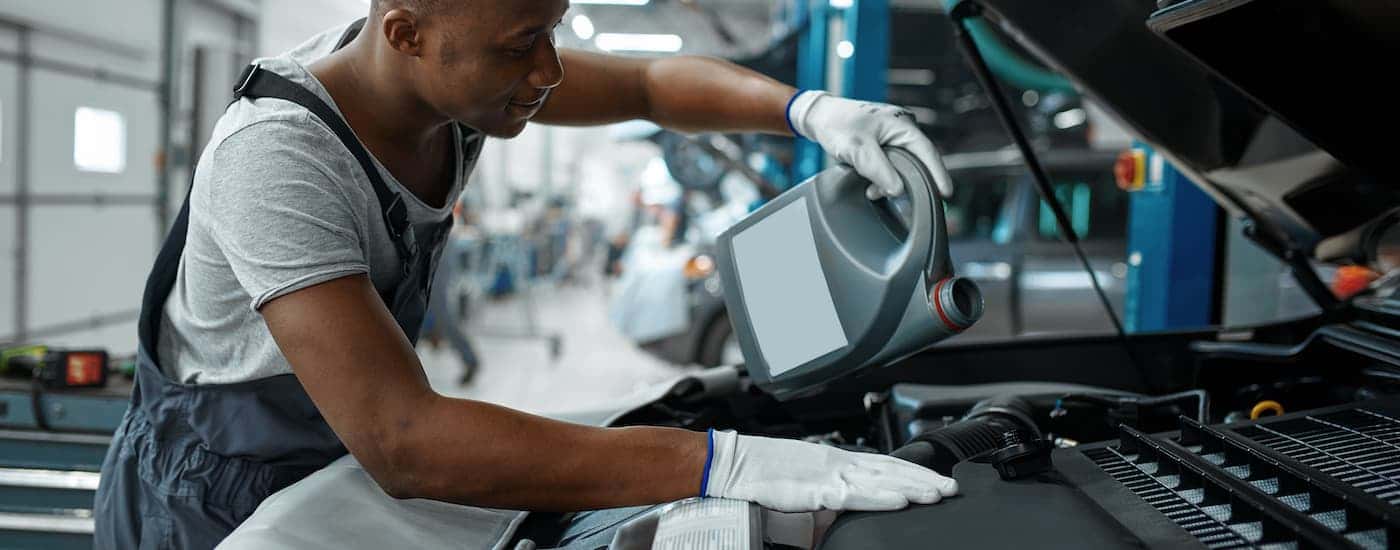 Technician pouring oil into an engine