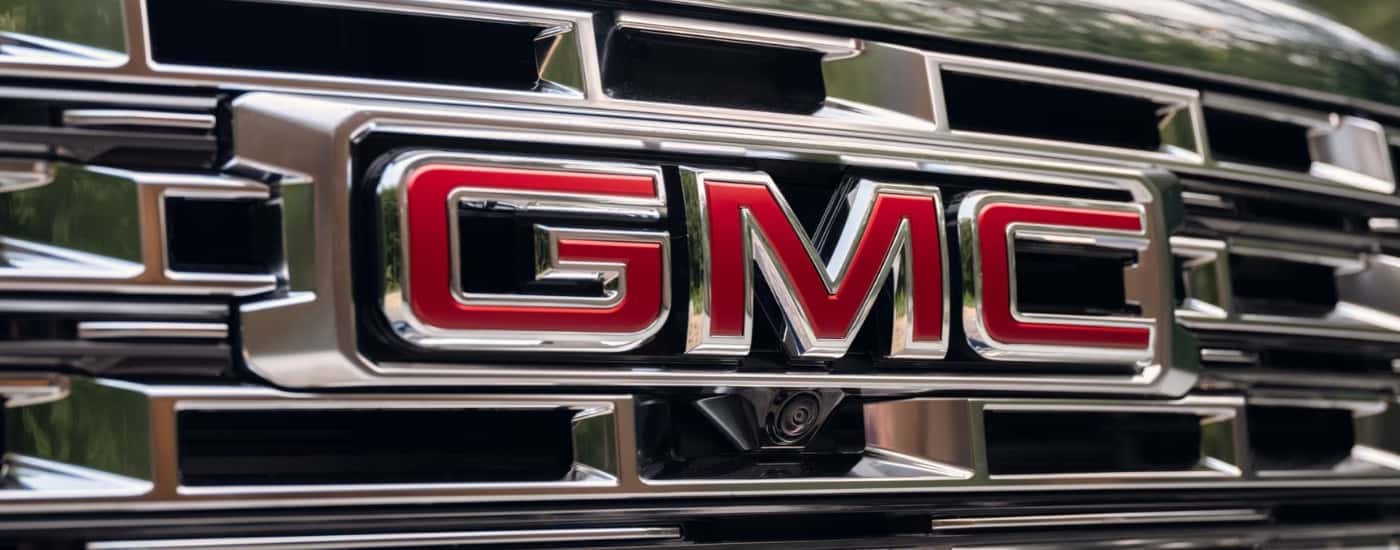 Chrome grille and red badging of a 2026 GMC Acadia Denali