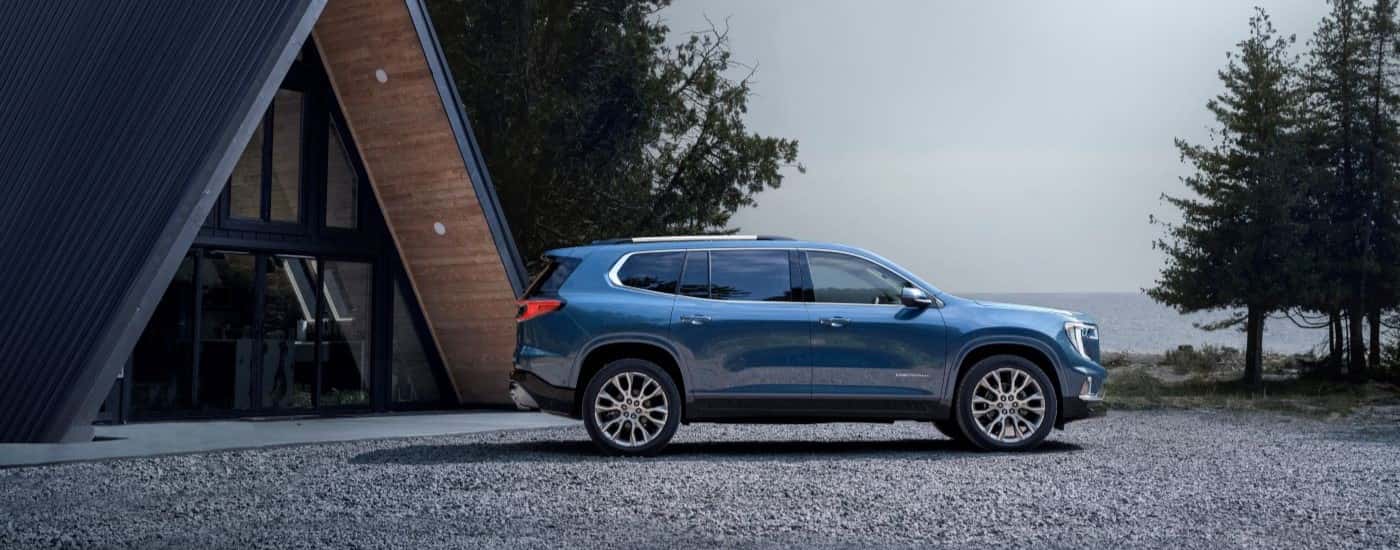 Blue 2026 GMC Acadia parked in front of an A-Frame house