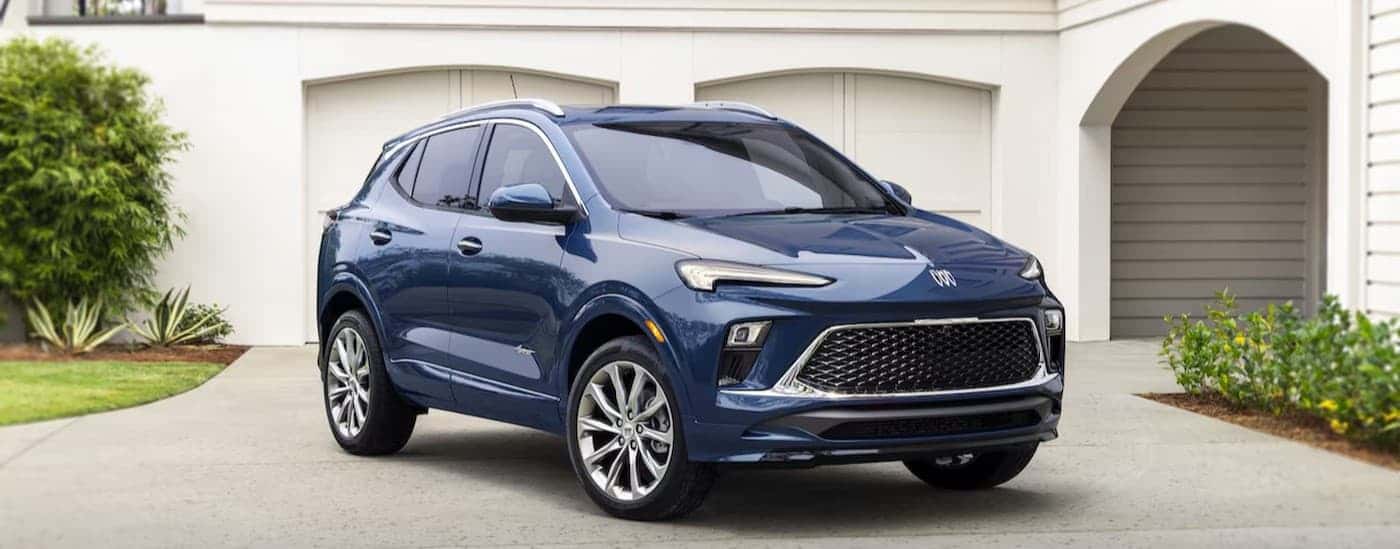 A blue 2024 Buick Encore GX Avenir parked near a garage.