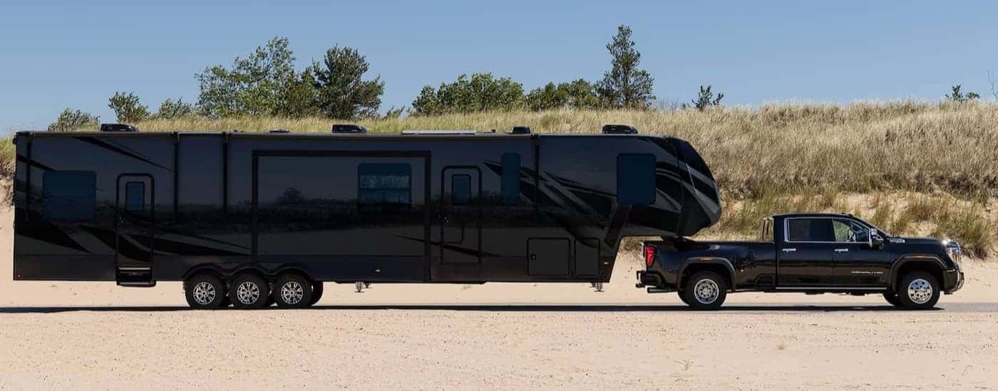A black 2026 GMC Sierra 3500 towing a long trailer.