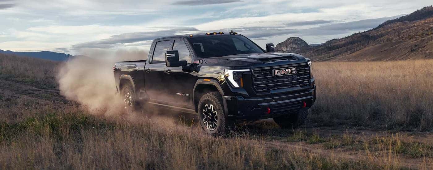 A black 2026 GMC Sierra 2500 AT4X HD off-roading on a trail