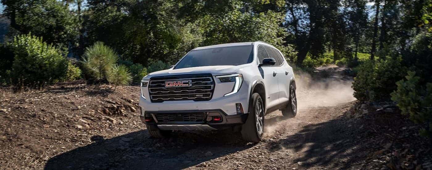 A white 2026 GMC Acadia AT4 driving offroad.