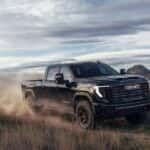 A black 2027 GMC Sierra 2500 HD driving offroad.