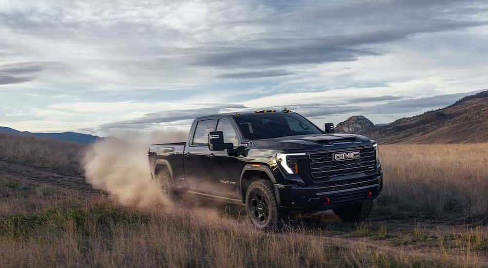 A black 2027 GMC Sierra 2500 HD driving offroad.