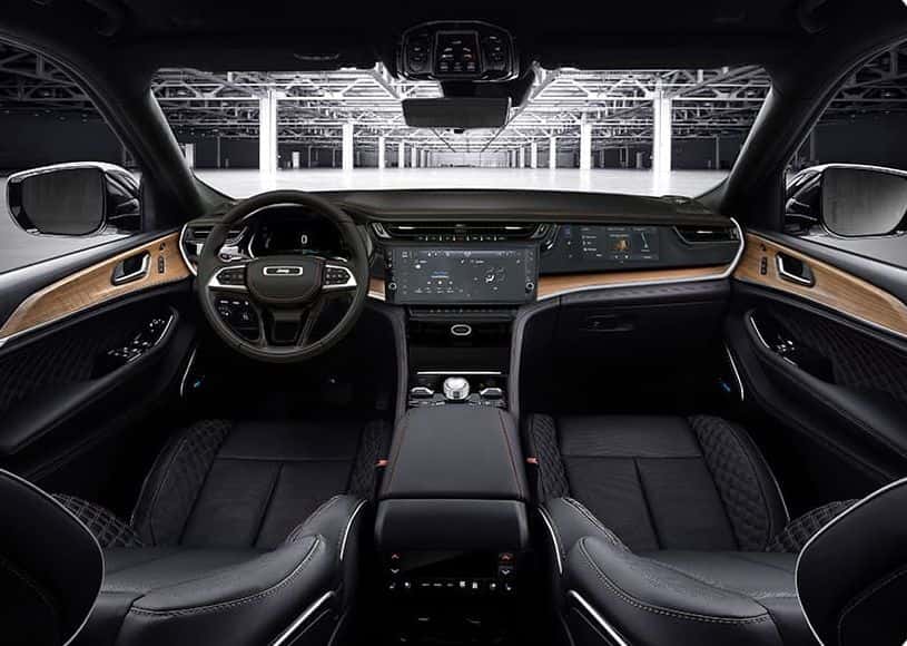 Black quilted leather front seats and wood-trimmed dashboard inside an upper-trim 2026 Jeep Grand Cherokee