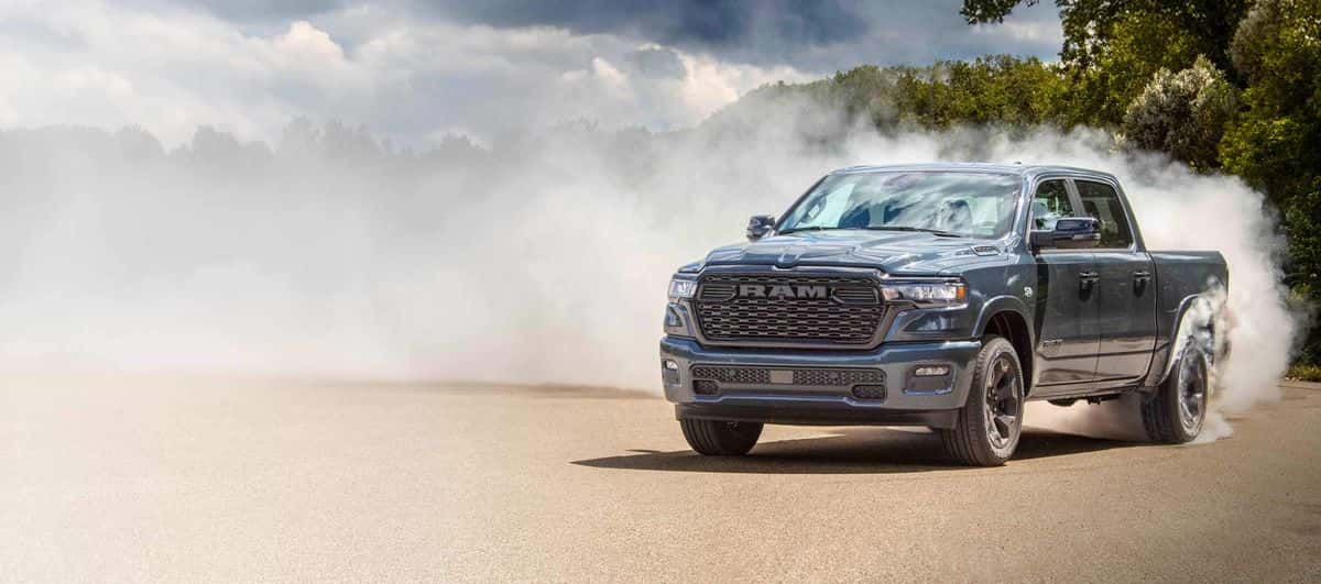 Forged Blue 2026 Ram 1500 Big Horn Night Edition kicking up smoke on a sandy road