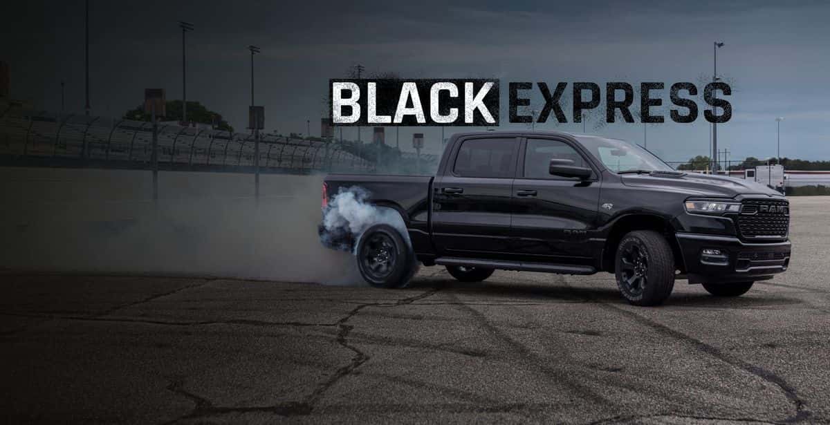 Black 2026 Ram 1500 Black Express 4x4 Crew Cab on a racetrack with tire smoke behind it