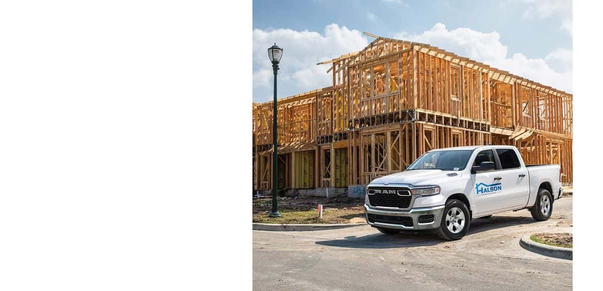 White 2026 Ram 1500 work truck parked beside a house under construction