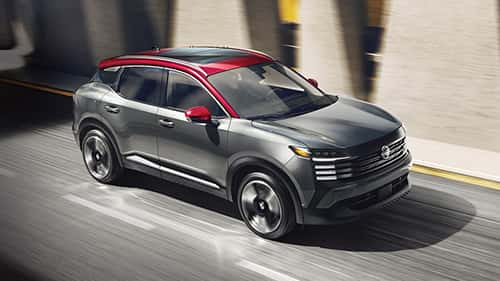 2026 nissan kicks driving down a road