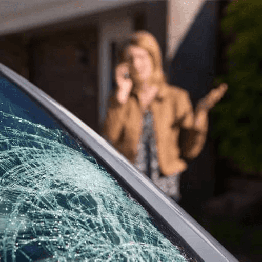 woman standing next to car with broken windshield