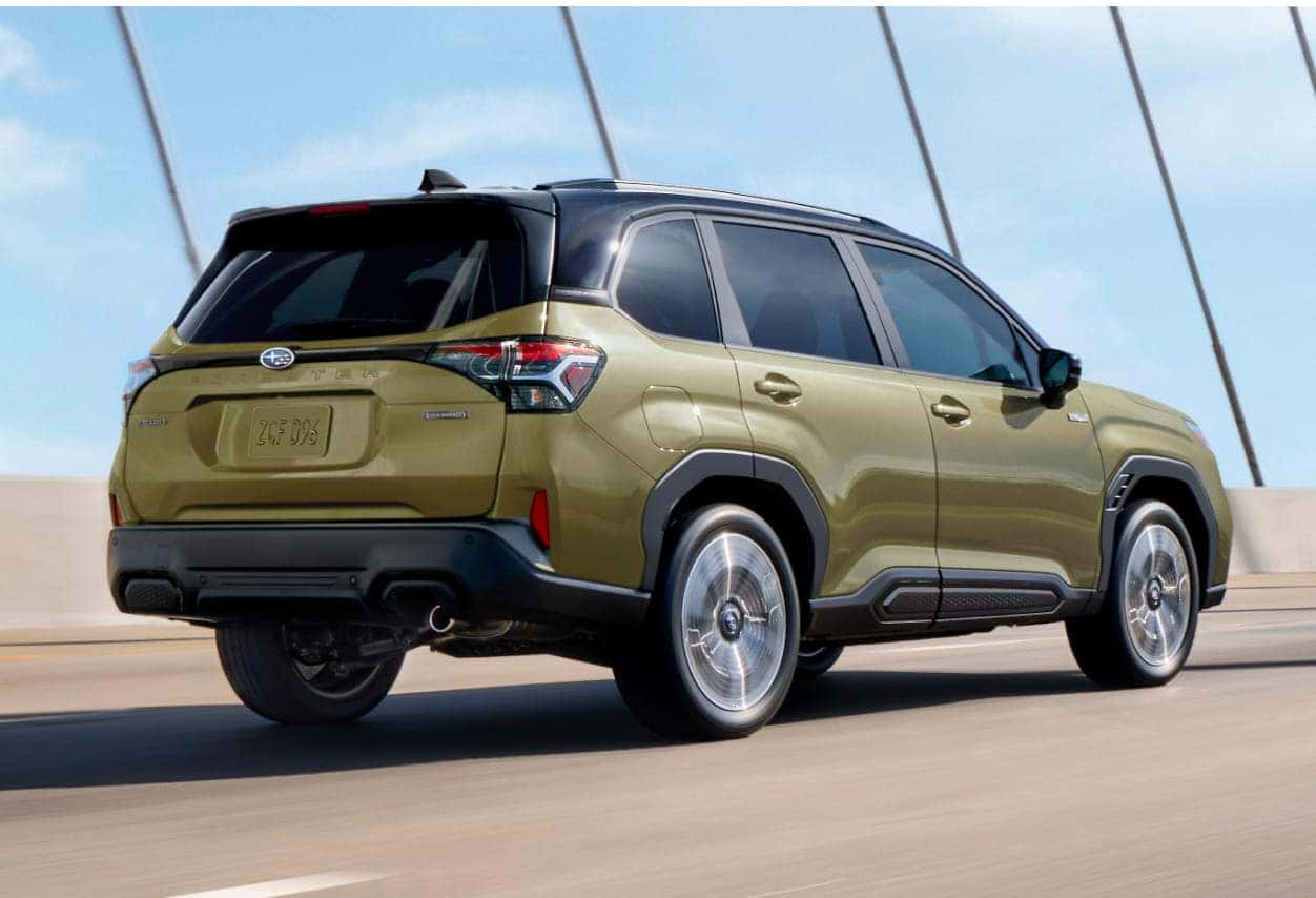 2026 Subaru Forester Hybrid drives on a bridge under a clear sky, showing off its sleek design and modern features. The scene conveys motion and adventure.