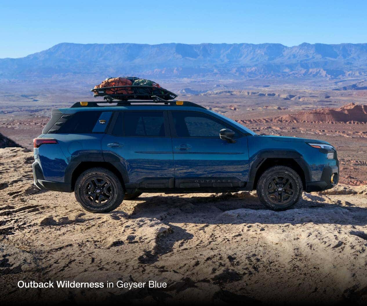 Subaru Outback Wilderness in Geyser Blue side profile with desert canyon in the background.