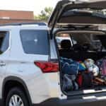 2026 Chevrolet Traverse with rear liftgate open at a school drop-off, packed with backpacks and sports gear