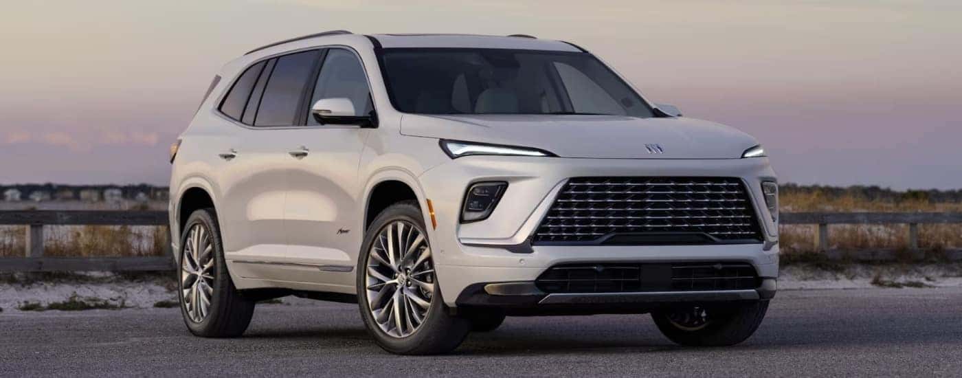 Wjite 2025 Buick Enclave parked against a fence