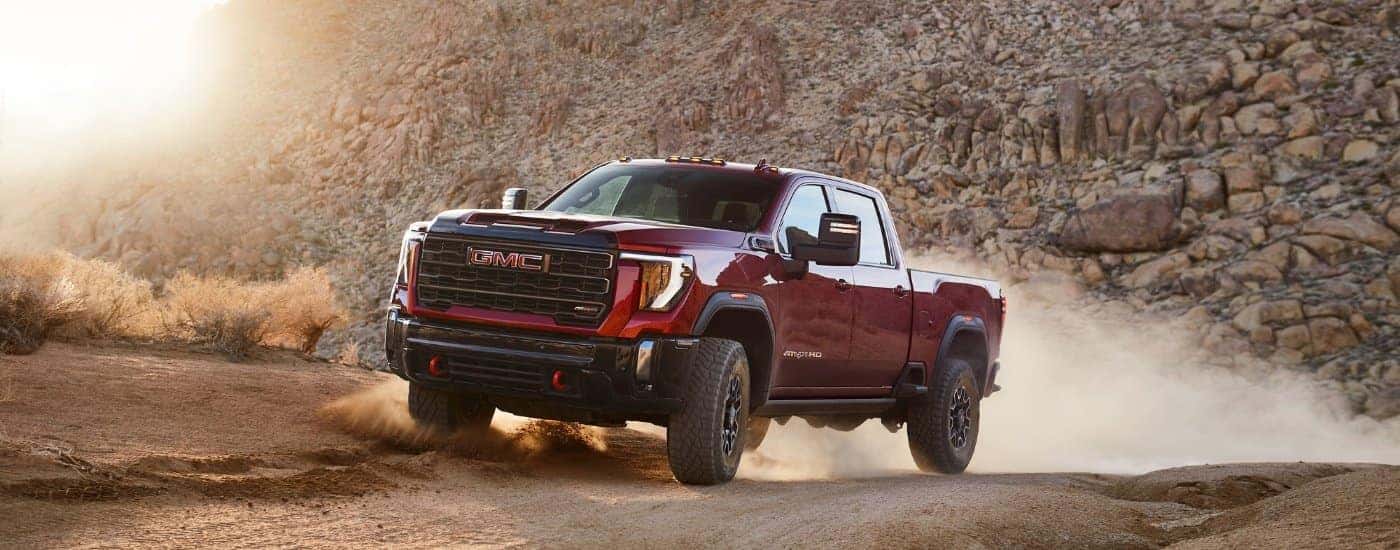 A red 2025 GMC Sierra 2500 from the side after leaving a GMC dealer.