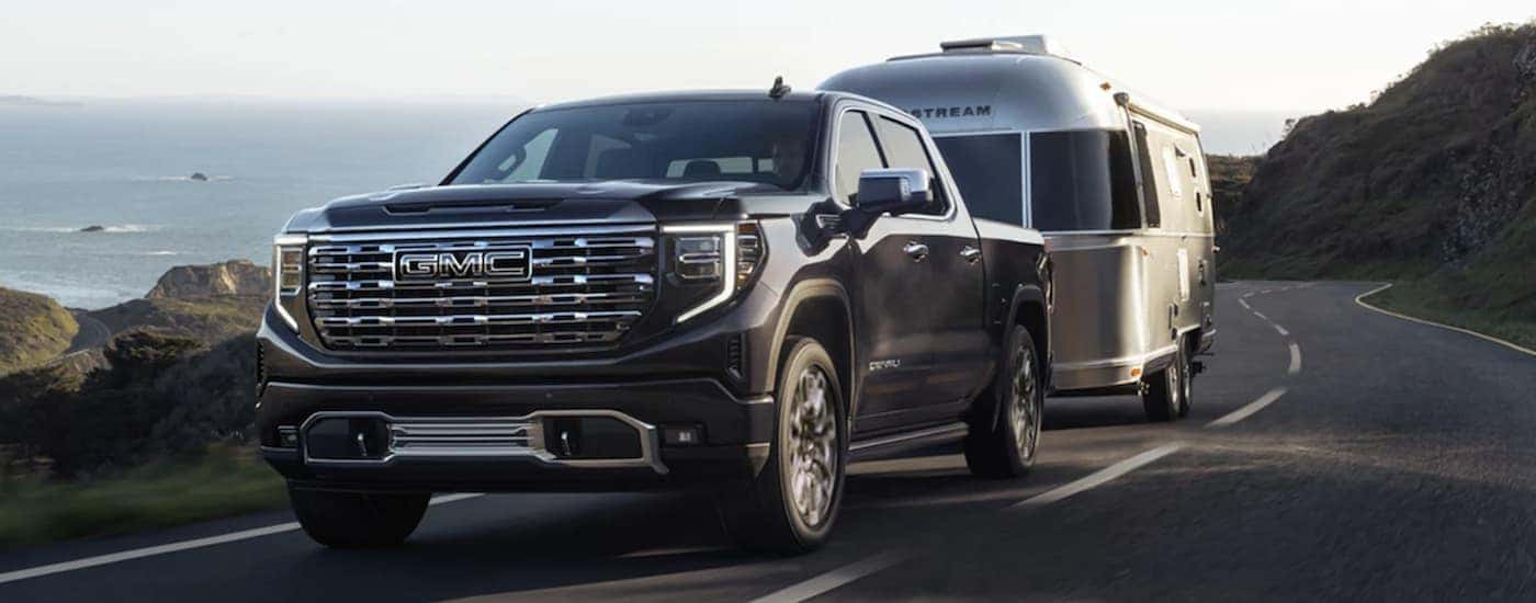 A black 2023 GMC Sierra 1500 Denali towing a camper