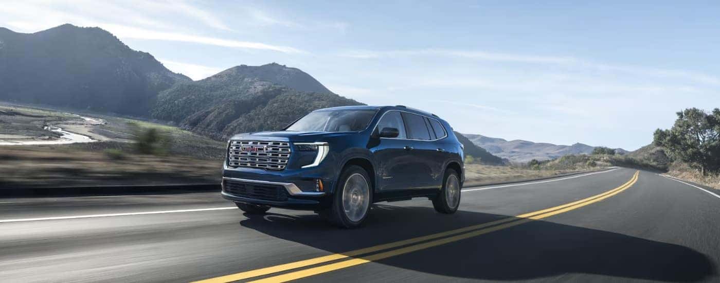 Blue 2025 GMC Acadia Denali driving to a GMC dealer near Apopka