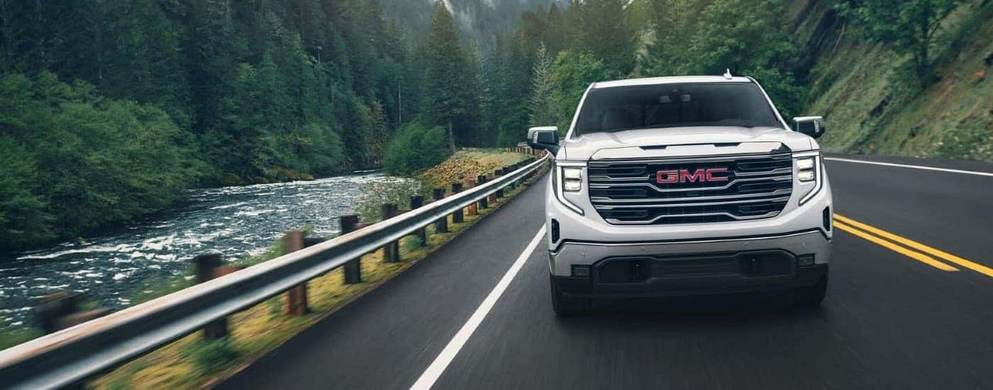 White 2025 GMC Sierra 1500 SLE driving down an open road.