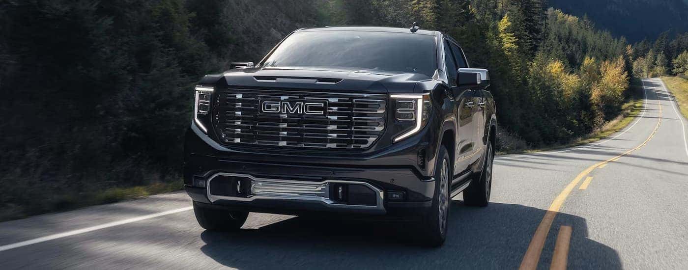 Black 2026 GMC Sierra 1500 Denali Ultimate driving down an open road.