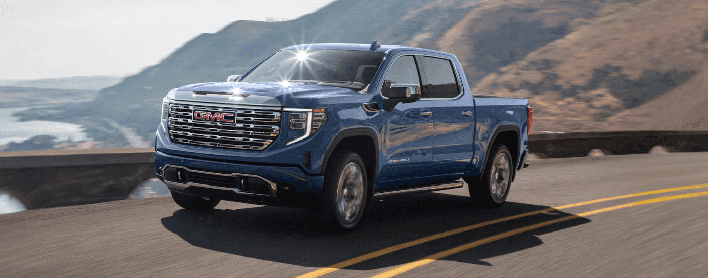 Blue 2026 GMC Sierra 1500 Denali driving along a coastline
