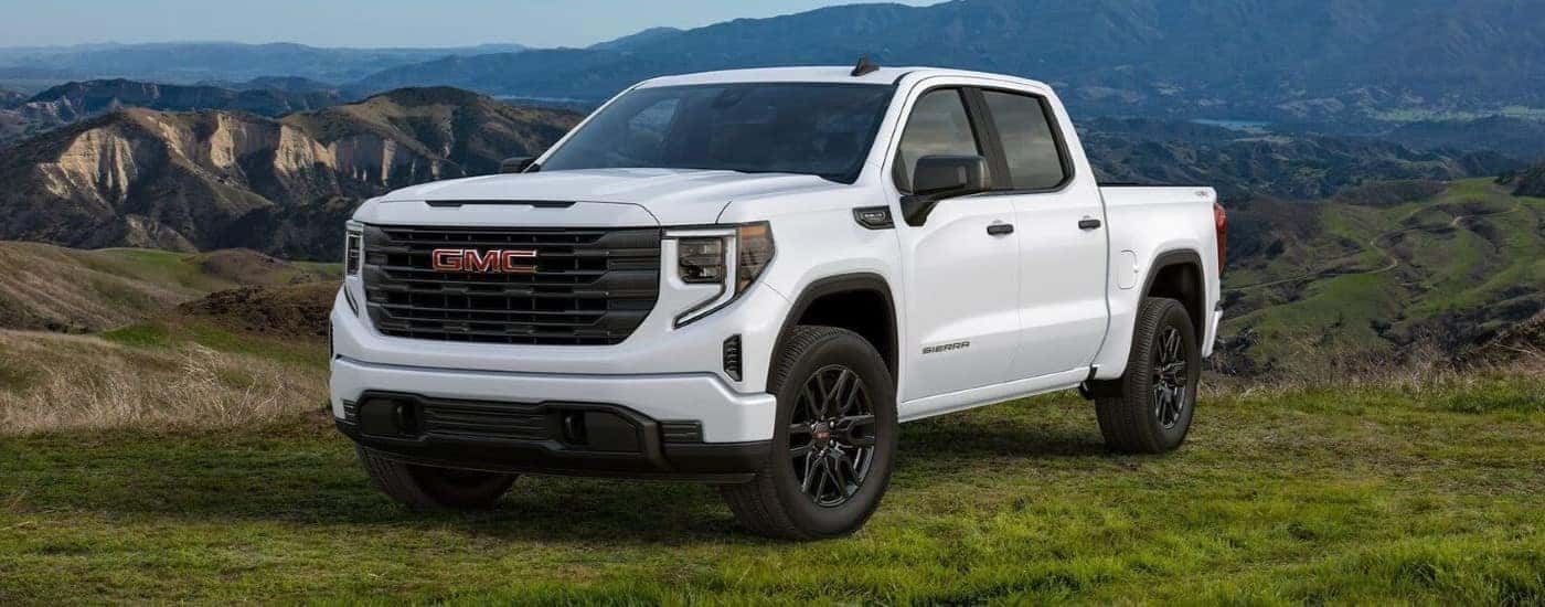 A white 2024 GMC Sierra 1500 Pro Graphite Edition parked on a grassy mountain.