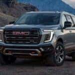 A gray 2026 GMC Yukon AT4 shown parked on dirt mountain terrain.