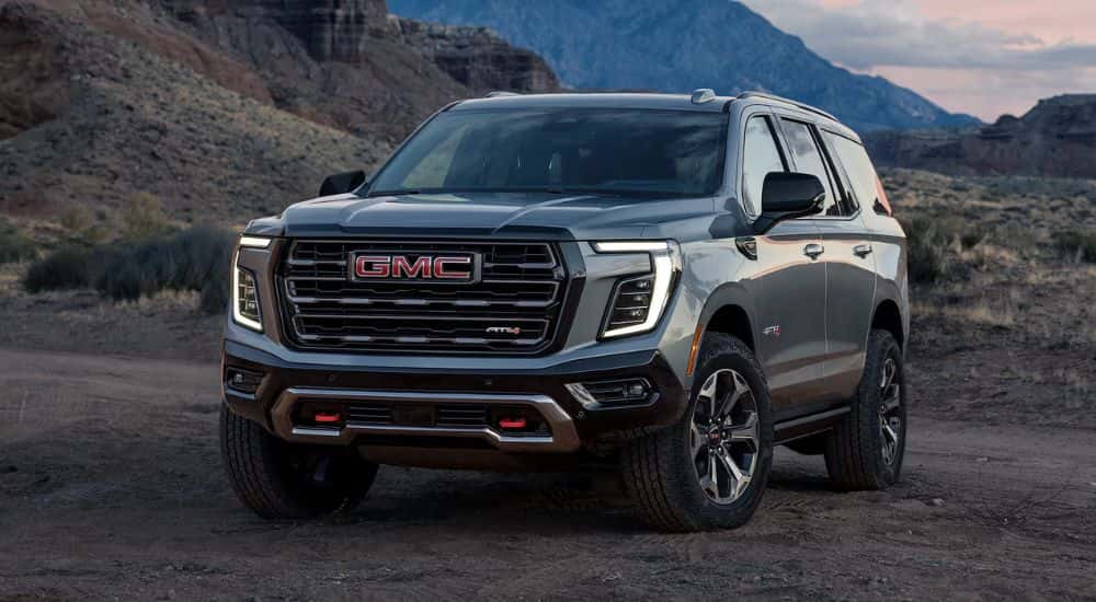 A gray 2026 GMC Yukon AT4 shown parked on dirt mountain terrain.