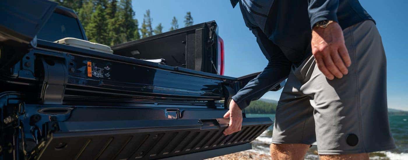 A man operating the Multi Pro Tailgate on a black 2026 GMC Sierra 1500.